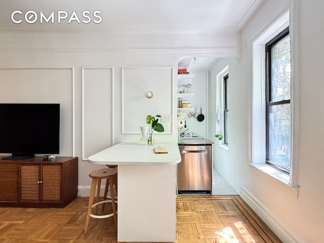 bar featuring stainless steel dishwasher, arched walkways, and baseboards