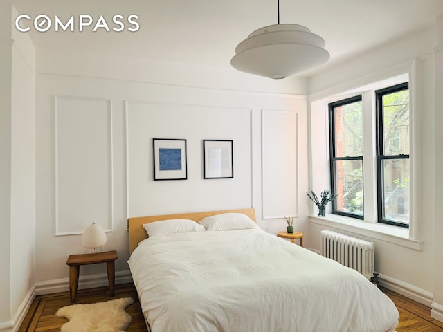 bedroom featuring baseboards, radiator, and wood finished floors
