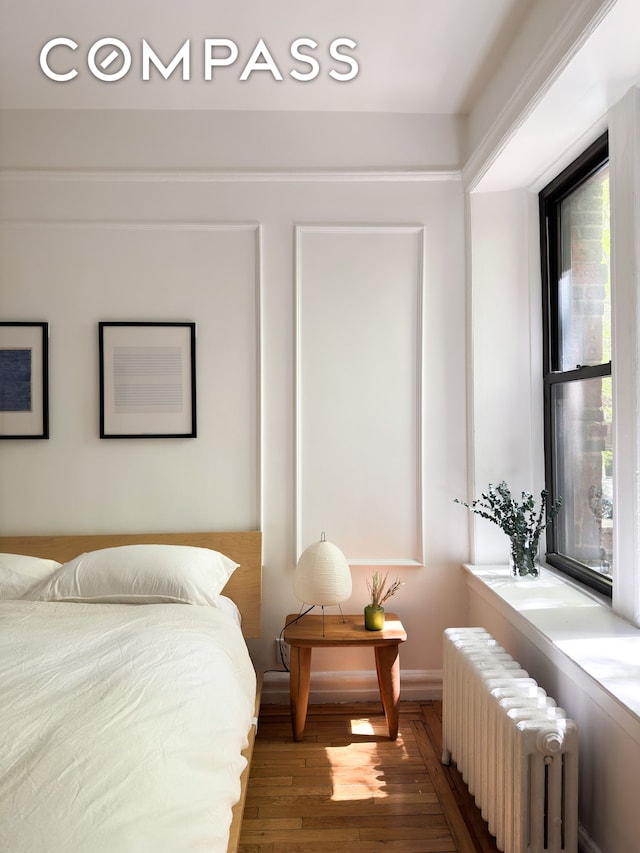 bedroom featuring radiator heating unit and wood finished floors