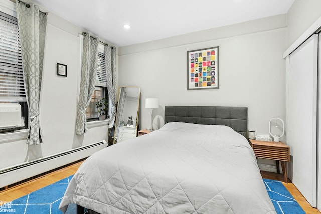 bedroom with wood finished floors, recessed lighting, and a baseboard heating unit