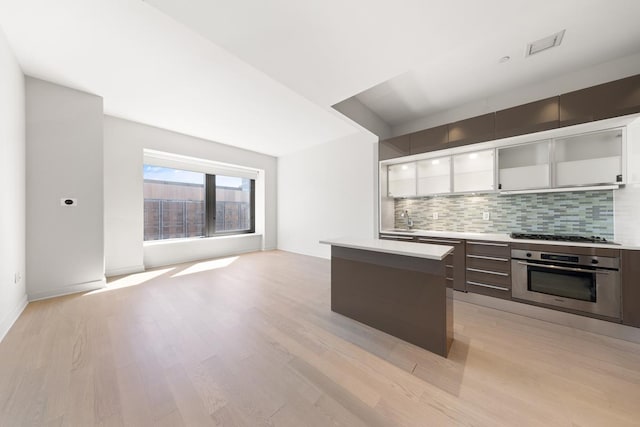 75 Wall St Unit 28-Q, New York City, NY 10005 - kitchen with appliances with stainless steel finishes, light wood finished floors, a center island, decorative backsplash, and modern cabinets