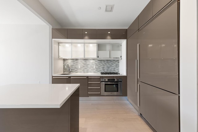 75 Wall St Unit 28-Q, New York City, NY 10005 - kitchen with appliances with stainless steel finishes, modern cabinets, decorative backsplash, and light countertops