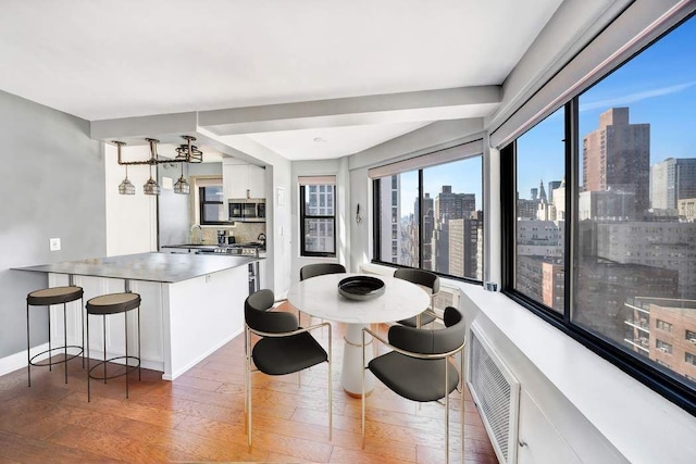 dining space featuring a view of city, baseboards, light wood-style flooring, and visible vents