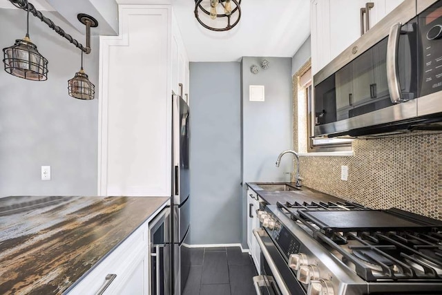 kitchen with backsplash, stainless steel appliances, dark countertops, and white cabinets