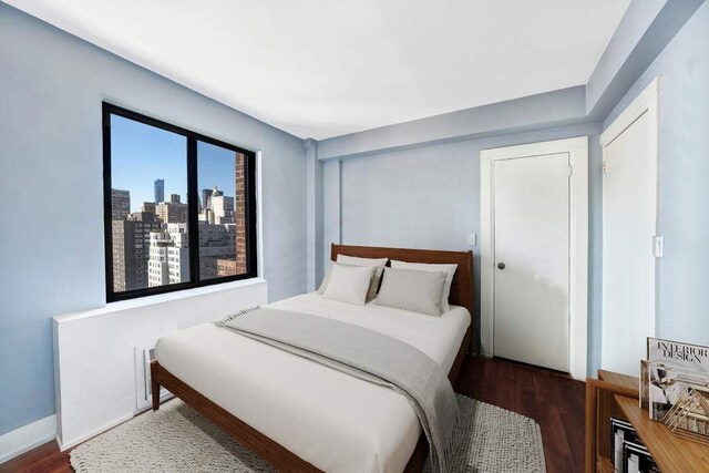 bedroom featuring a city view and wood finished floors