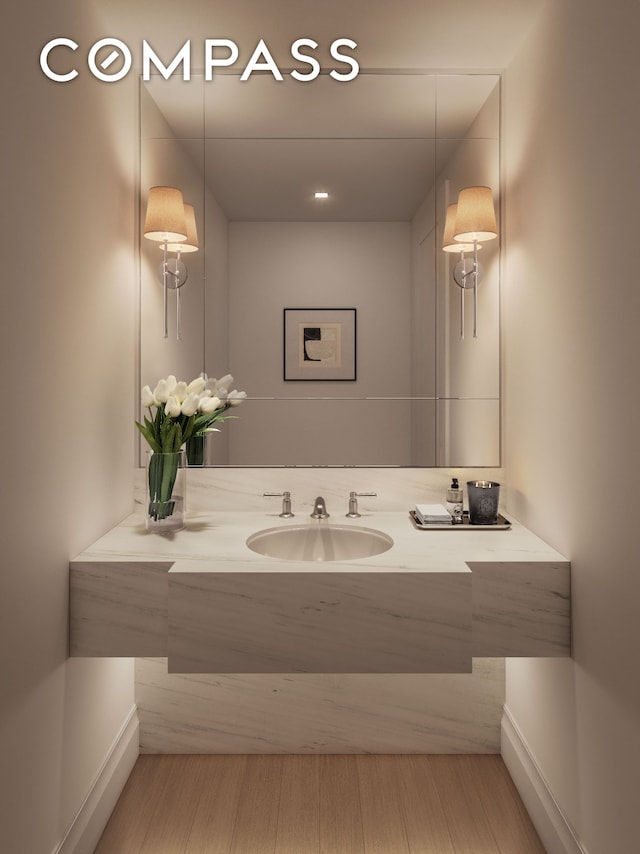 bathroom featuring baseboards, wood finished floors, and vanity