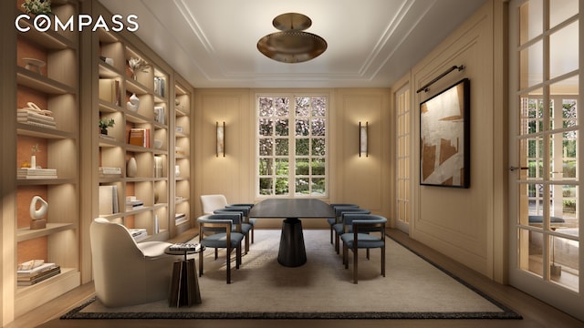 living area featuring built in shelves, wood finished floors, and a decorative wall