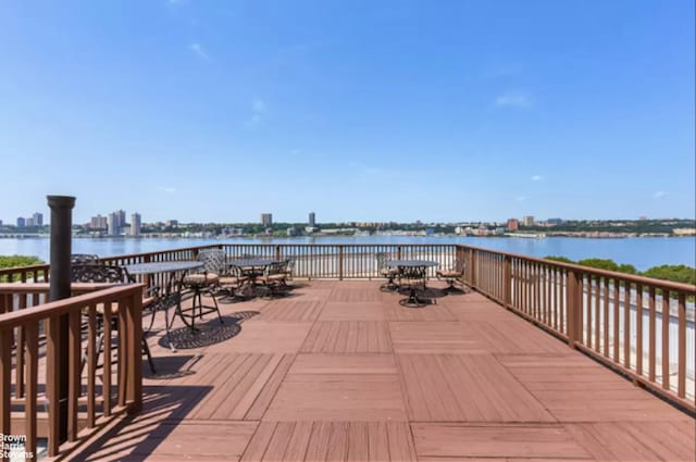 wooden terrace with outdoor dining space and a water view