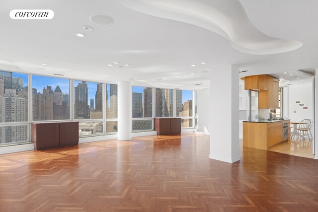 unfurnished living room with a view of skyline, baseboards, recessed lighting, and expansive windows