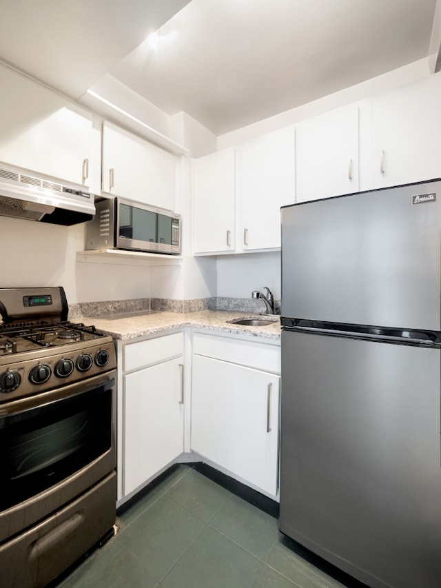 kitchen with a sink, stainless steel appliances, white cabinetry, and under cabinet range hood
