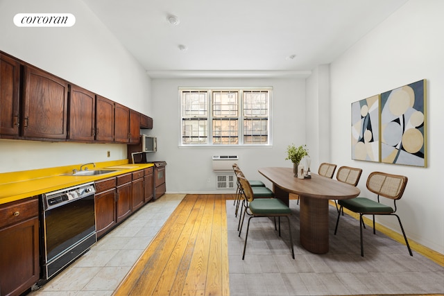 kitchen featuring black dishwasher, range with gas stovetop, a sink, light countertops, and light wood-type flooring