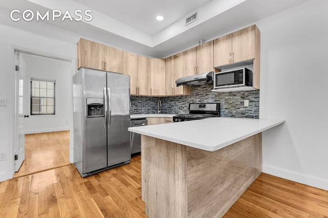 kitchen with baseboards, light brown cabinetry, under cabinet range hood, and stainless steel appliances