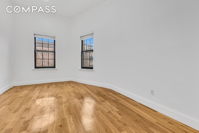 empty room featuring light wood-style floors, baseboards, and a wealth of natural light
