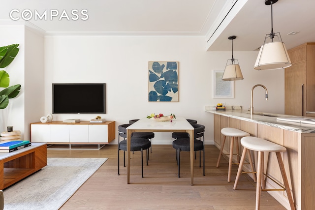 playroom with crown molding, a sink, light wood-type flooring, and baseboards