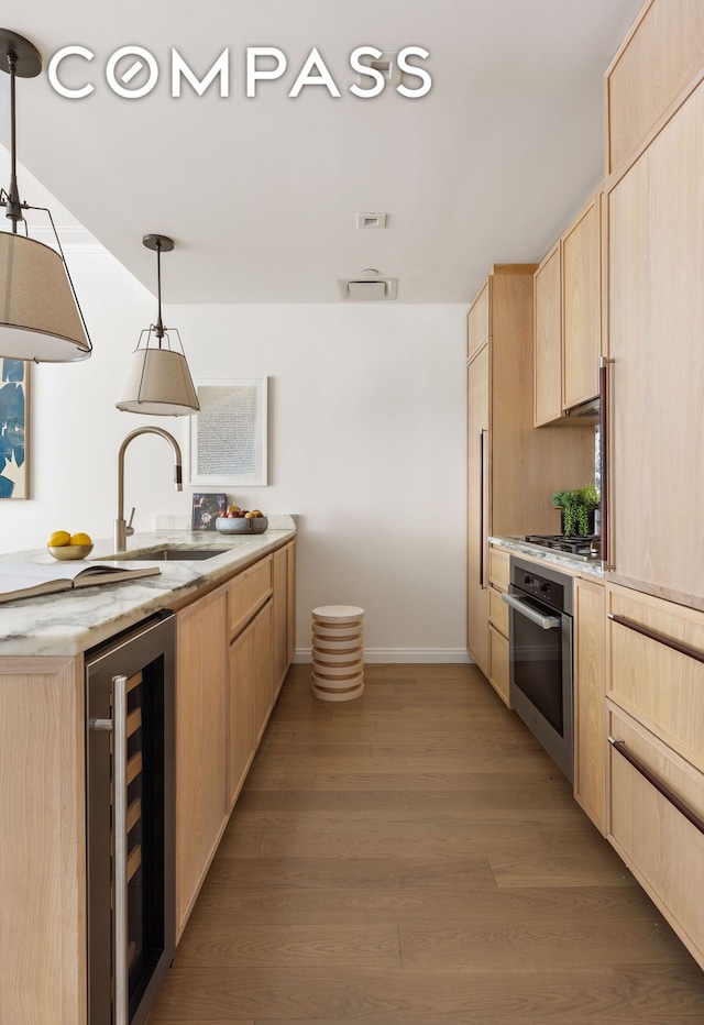 kitchen featuring oven, light brown cabinetry, wine cooler, a sink, and light wood-style floors