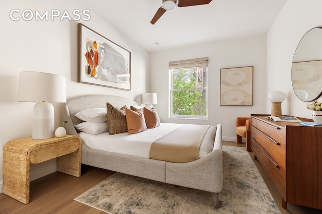 bedroom featuring wood finished floors, a ceiling fan, and baseboards