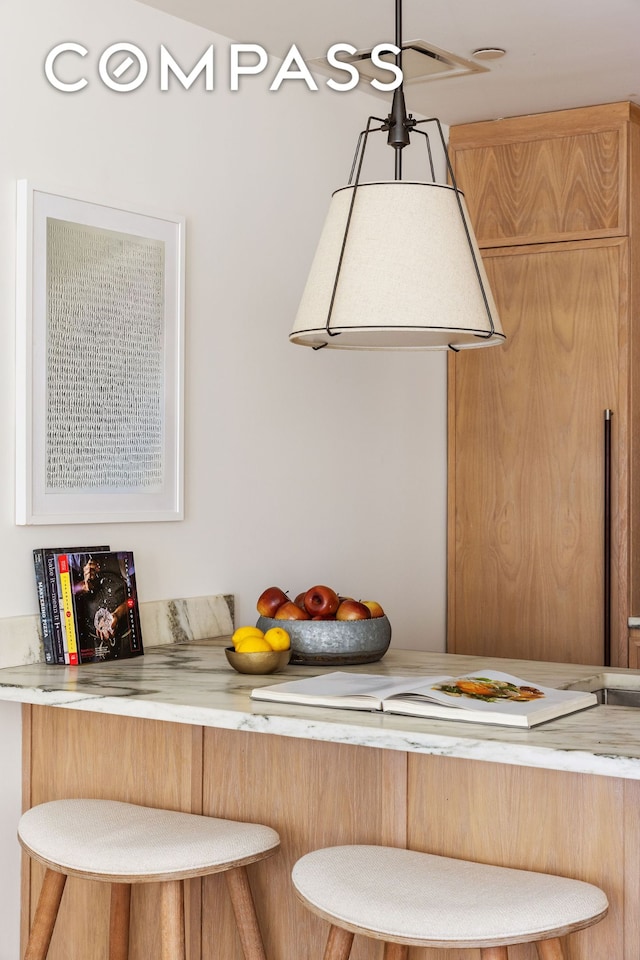 kitchen with a breakfast bar area, light countertops, and hanging light fixtures
