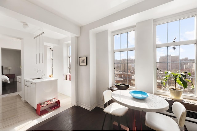 dining room featuring light wood-style flooring, baseboards, and a city view