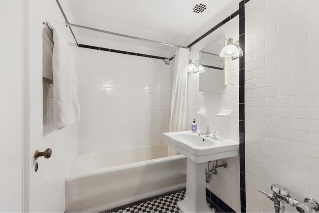 full bath with tile walls, shower / tub combo with curtain, and tile patterned floors