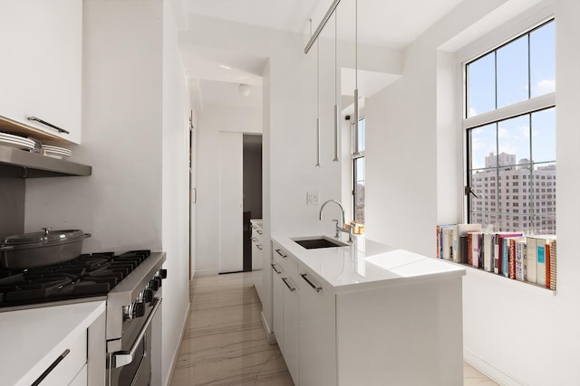 kitchen with a sink, gas range, modern cabinets, light marble finish flooring, and white cabinets