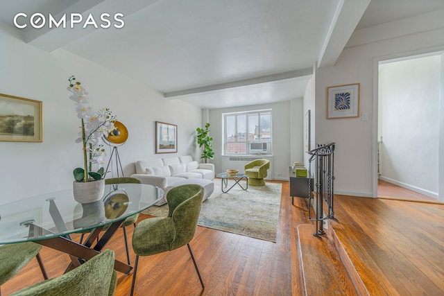 dining room featuring beamed ceiling, hardwood / wood-style floors, and baseboards
