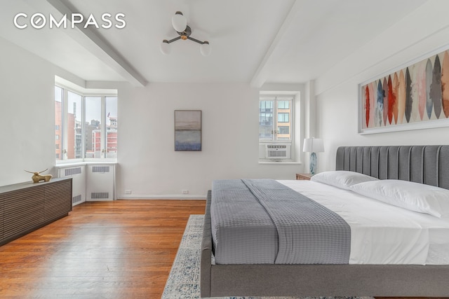 bedroom featuring radiator, wood finished floors, beamed ceiling, cooling unit, and baseboards