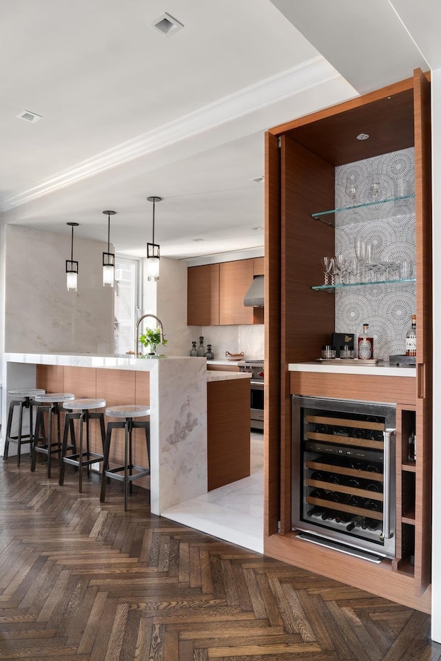bar featuring beverage cooler, wall chimney range hood, stainless steel range oven, visible vents, and a bar