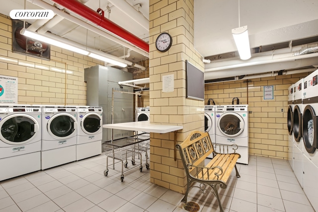 shared laundry with washing machine and dryer, tile patterned floors, and tile walls