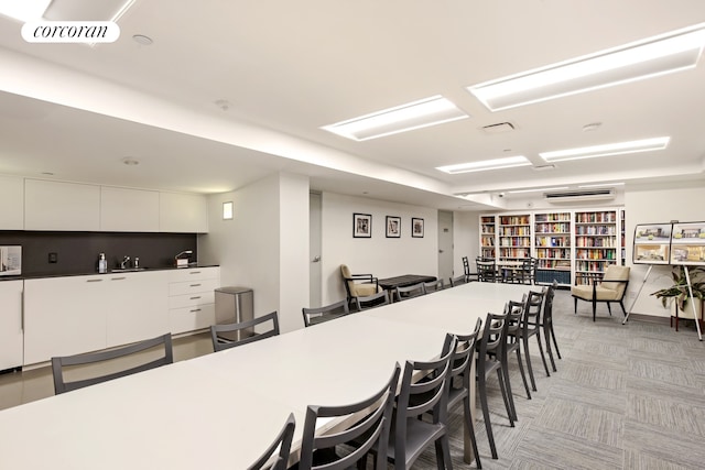kitchen with a breakfast bar, white cabinets, a sink, light colored carpet, and modern cabinets