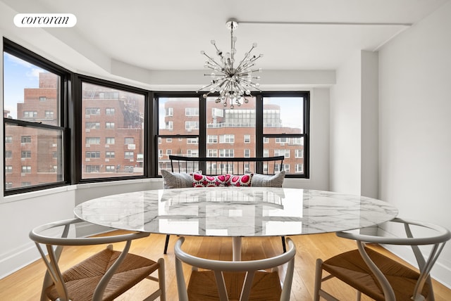 dining space with a chandelier, wood finished floors, and baseboards