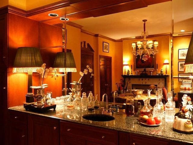 bar featuring crown molding, wet bar, a sink, and an inviting chandelier