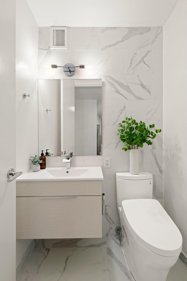 235 E 40th St Unit 6B, New York City, NY 10016 - half bath featuring vanity, toilet, tile walls, and marble finish flooring