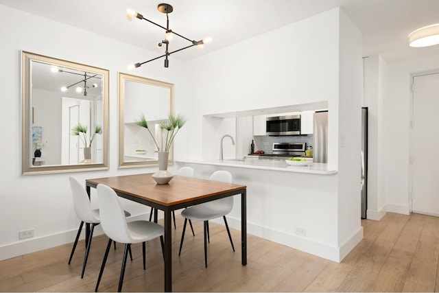 dining space with a chandelier, light wood-style flooring, and baseboards