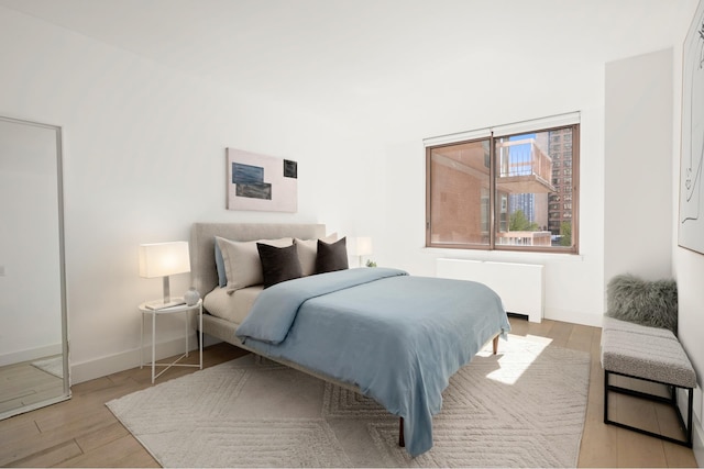 bedroom featuring radiator heating unit, wood finished floors, and baseboards