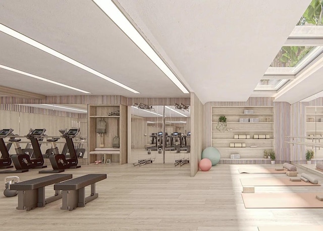 exercise room with wood finished floors, wood walls, and a skylight