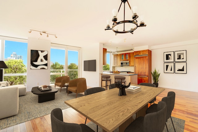 dining room with track lighting, baseboards, light wood-type flooring, and a chandelier