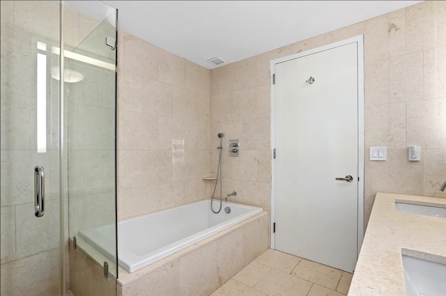full bath featuring a sink, visible vents, tile walls, and double vanity