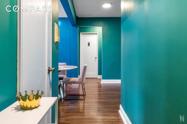 hall featuring baseboards and dark wood-style flooring