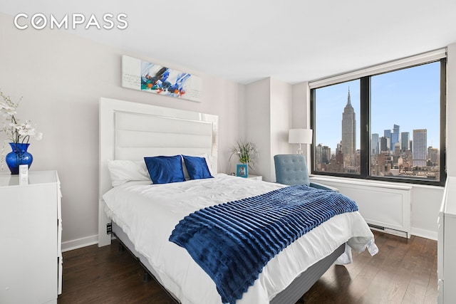 330 E 38th St Unit 50E, New York City, NY 10016 - bedroom featuring wood finished floors, a view of skyline, and baseboards