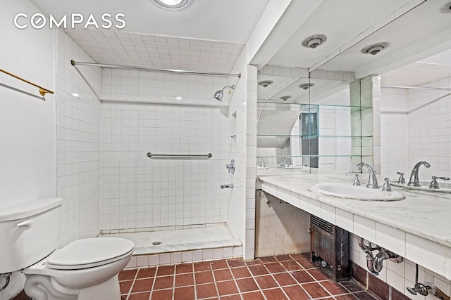 full bathroom featuring tile patterned flooring, vanity, tiled shower, and toilet