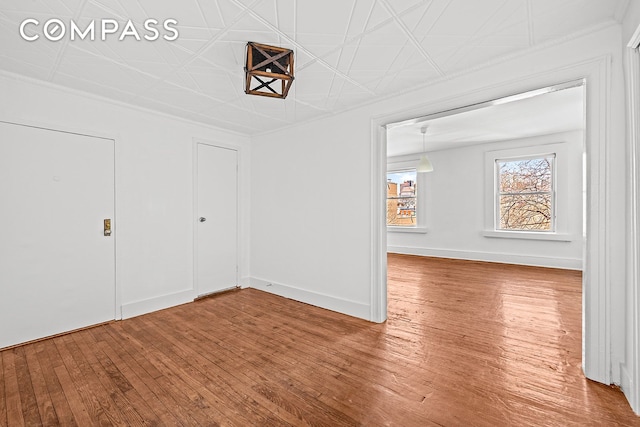 unfurnished dining area featuring wood finished floors, ornamental molding, and an ornate ceiling
