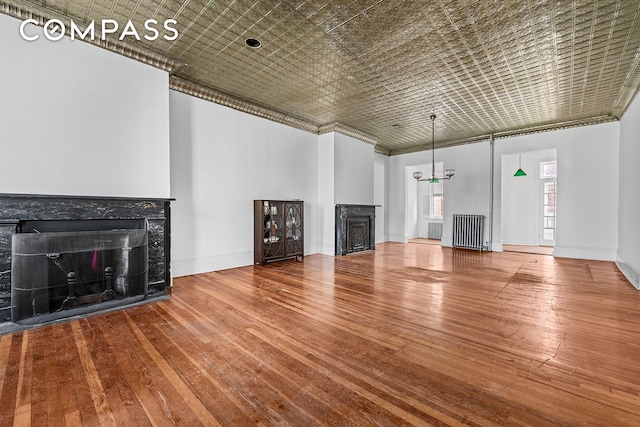 unfurnished living room featuring radiator heating unit, a fireplace, baseboards, and hardwood / wood-style flooring