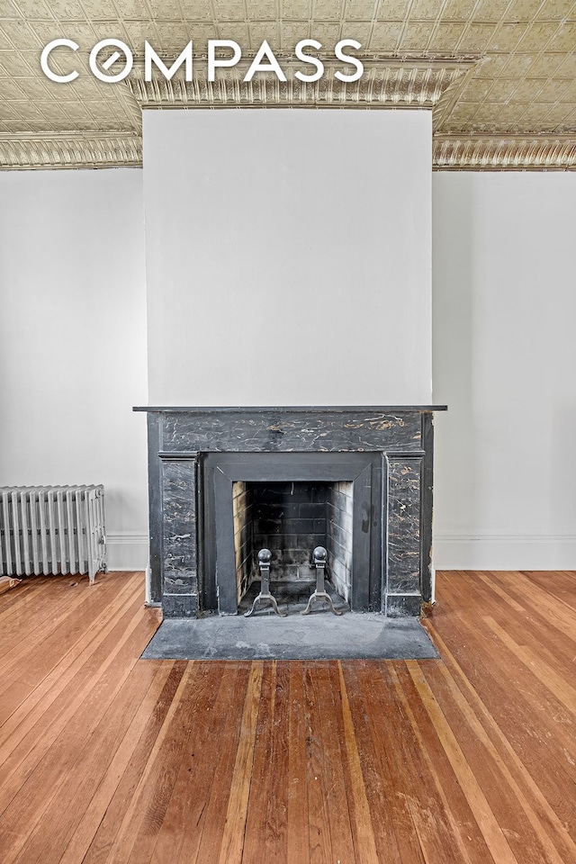room details with radiator heating unit, wood finished floors, and baseboards
