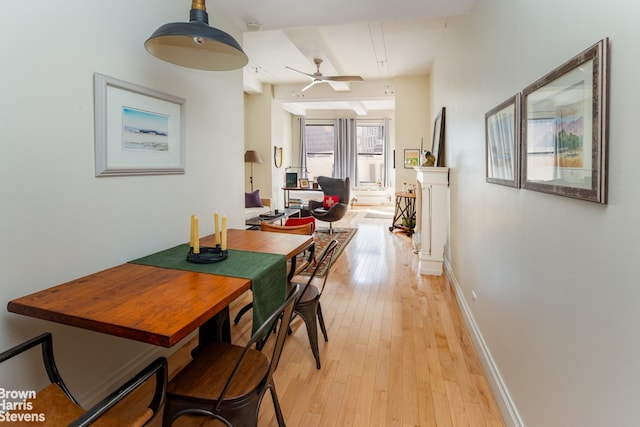 dining area with baseboards, a ceiling fan, and light wood finished floors
