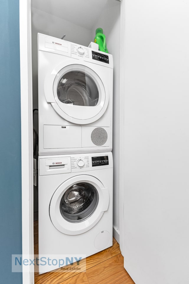 clothes washing area with estacked washer and dryer and wood finished floors