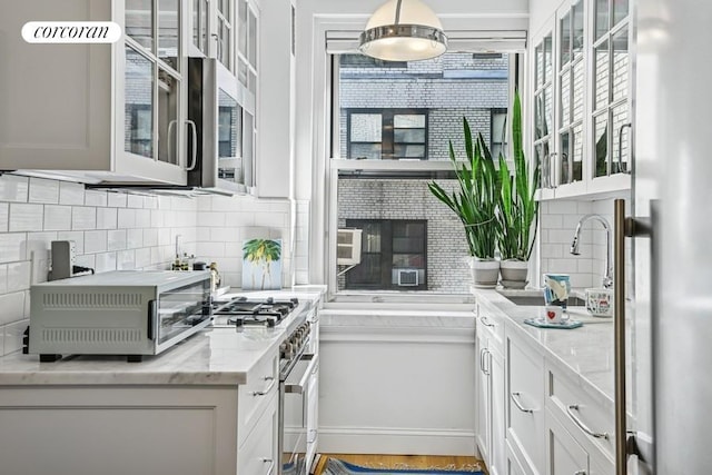 kitchen with backsplash, stainless steel range, a sink, refrigerator, and glass insert cabinets