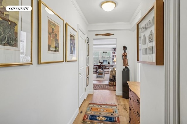 hallway with light wood-style flooring and ornamental molding