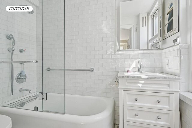 full bath featuring tile walls, bath / shower combo with glass door, toilet, and vanity