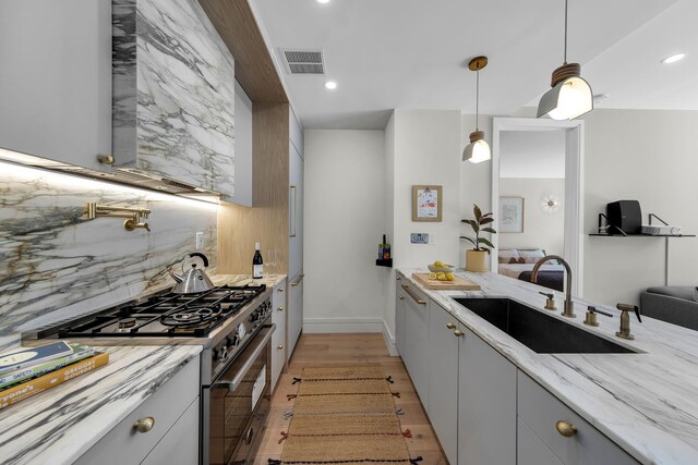 114 Lexington Ave Unit 203, New York City, NY 11238 - kitchen featuring high end stainless steel range oven, a sink, tasteful backsplash, recessed lighting, and light stone countertops