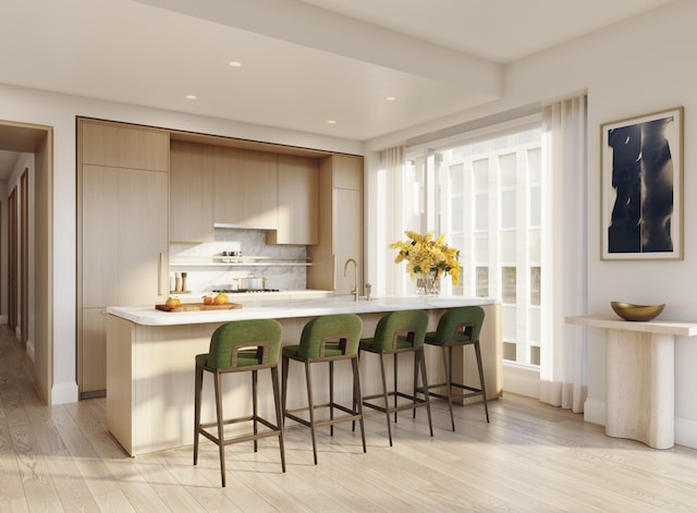 kitchen with backsplash, light countertops, light wood-type flooring, and a breakfast bar area